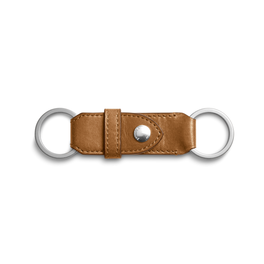 The Shinola Leather Valet Key Fob in brown features two silver metal rings on each end and a central snap button, showcased against a white background.