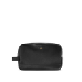The Shinola Zip Travel Kit - Dominos is a black natural grain leather toiletry bag with a side handle, gold-tone studs, subtle embossed logo, water-resistant lining, and zip closure, shown on a plain white background.