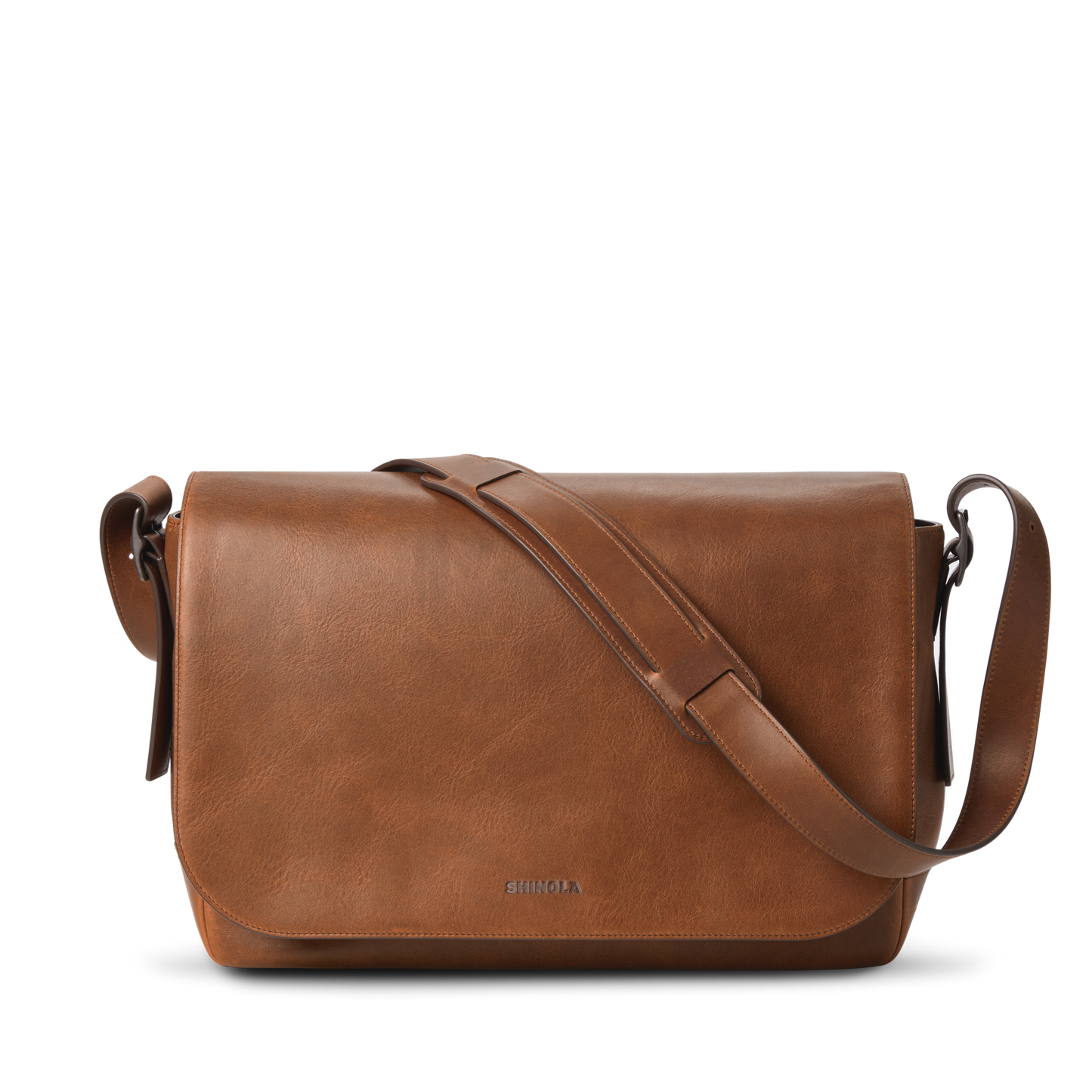 The Runwell Messenger Bag in medium brown by Shinola features a large flap closure, an adjustable crossbody strap, and the Shinola logo embossed near the bottom center. Displayed on a white background.