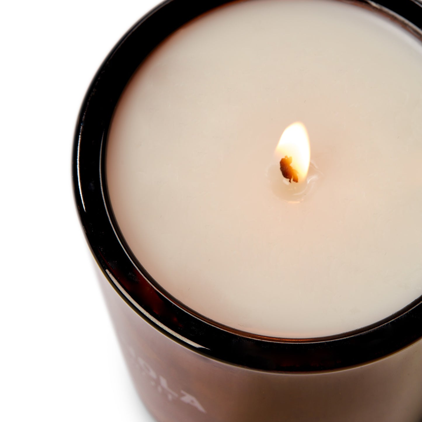A close-up of the Shinola Smoke 8oz Scented Candle in a dark glass container, with its flame glowing at the center of the smooth coconut soy wax surface.