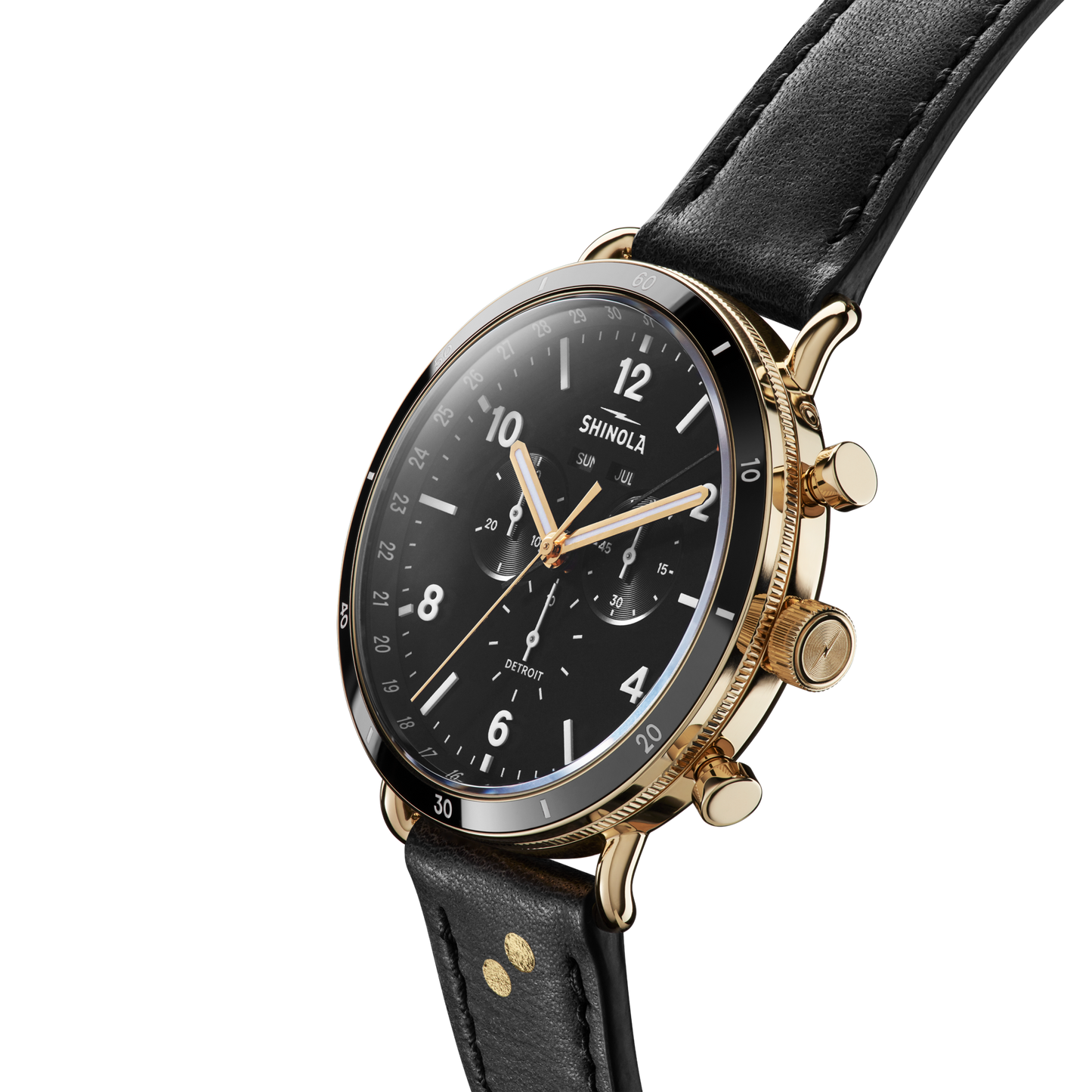 A close-up of the Shinola Canfield Sport Watch - Dominos featuring a black leather strap, gold case, black dial with white numerals, three subdials, and three gold pushers, displayed against a white background.