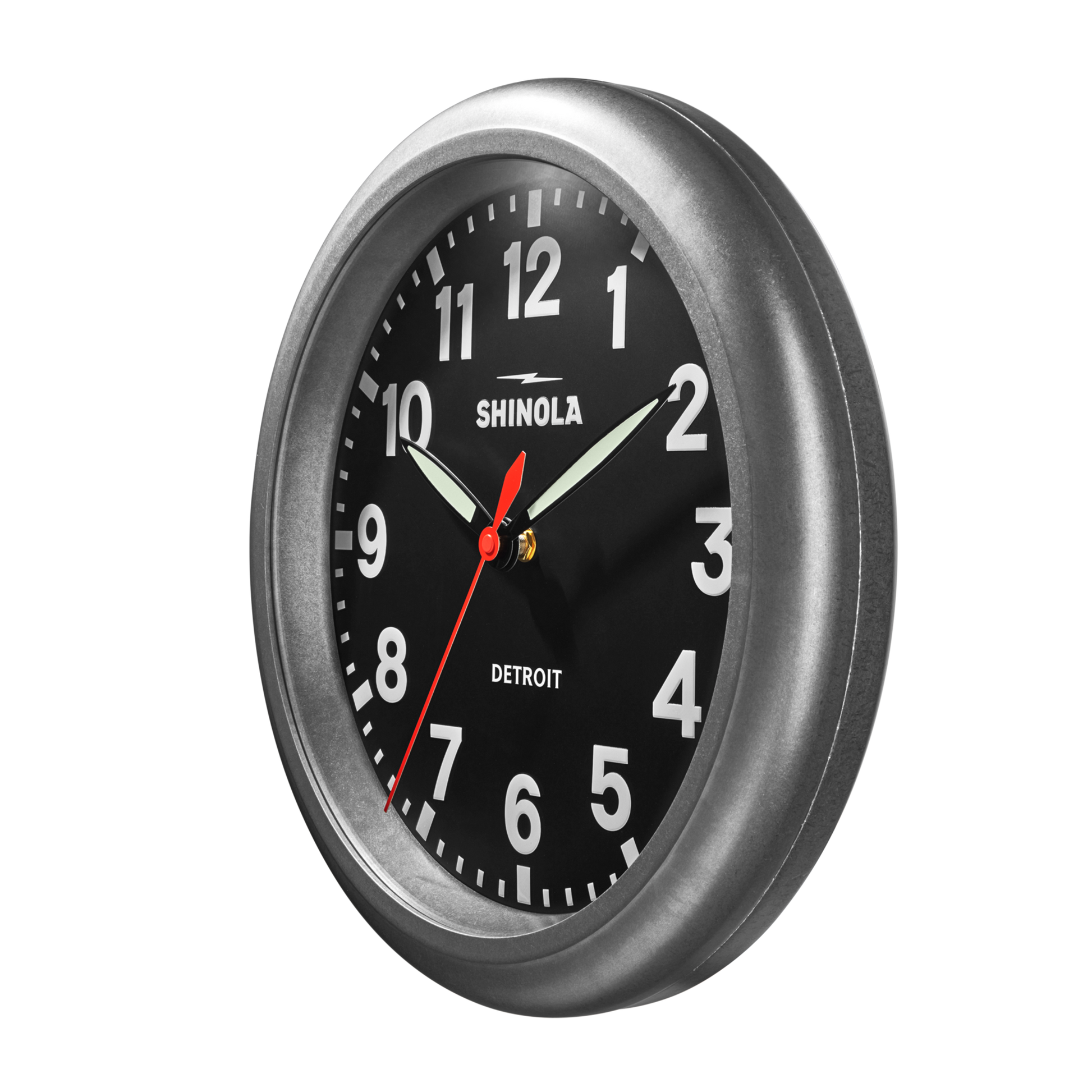 The Shinola 14" Runwell Clock features a tumbled zinc casing, black face, white numbers, and three hands. “Shinola” and “Detroit” are visible on the clock, which displays approximately 10:09:34.