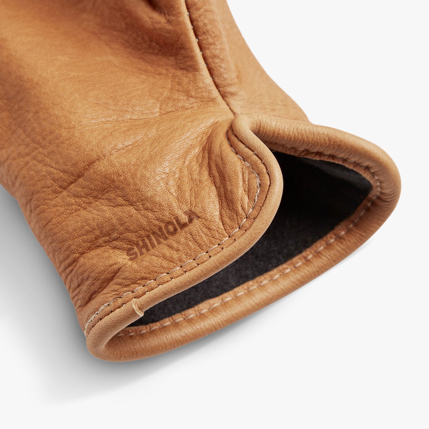 Close-up of the cuff of Shinola Lined Leather Gloves - Tan, showing visible stitching and SHINOLA embossed near the edge; these fleece-lined gloves are crafted for comfort.