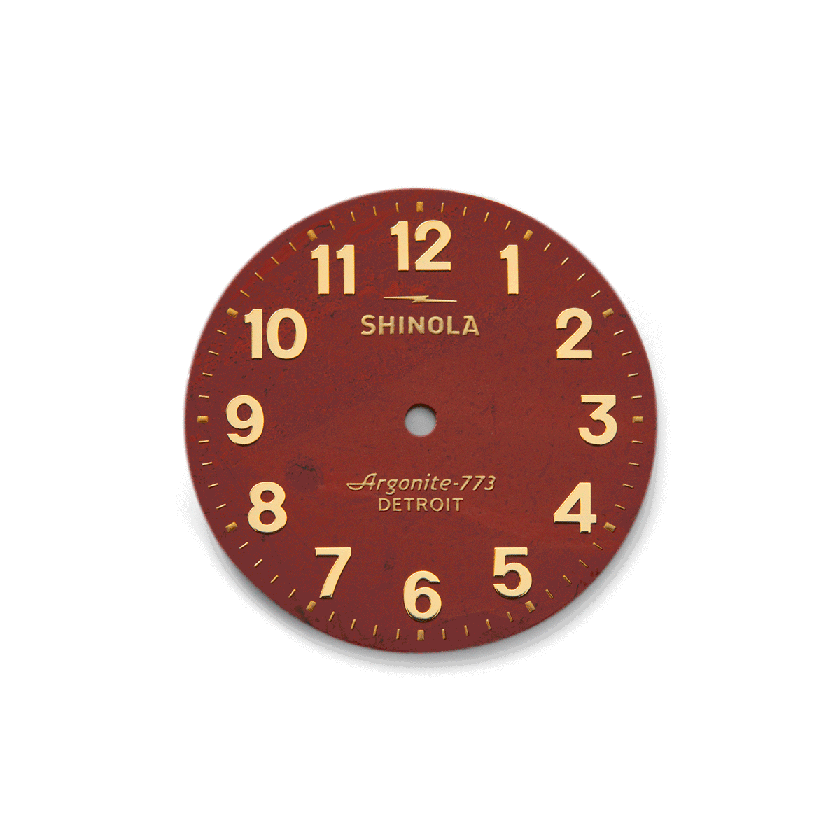 The Shinola Birdy Watch - Red Jasper features a round, red jasper stone face with gold numbers, tick marks, and "Argonite-773 DETROIT" text. This handless timepiece is shown isolated on a white background.