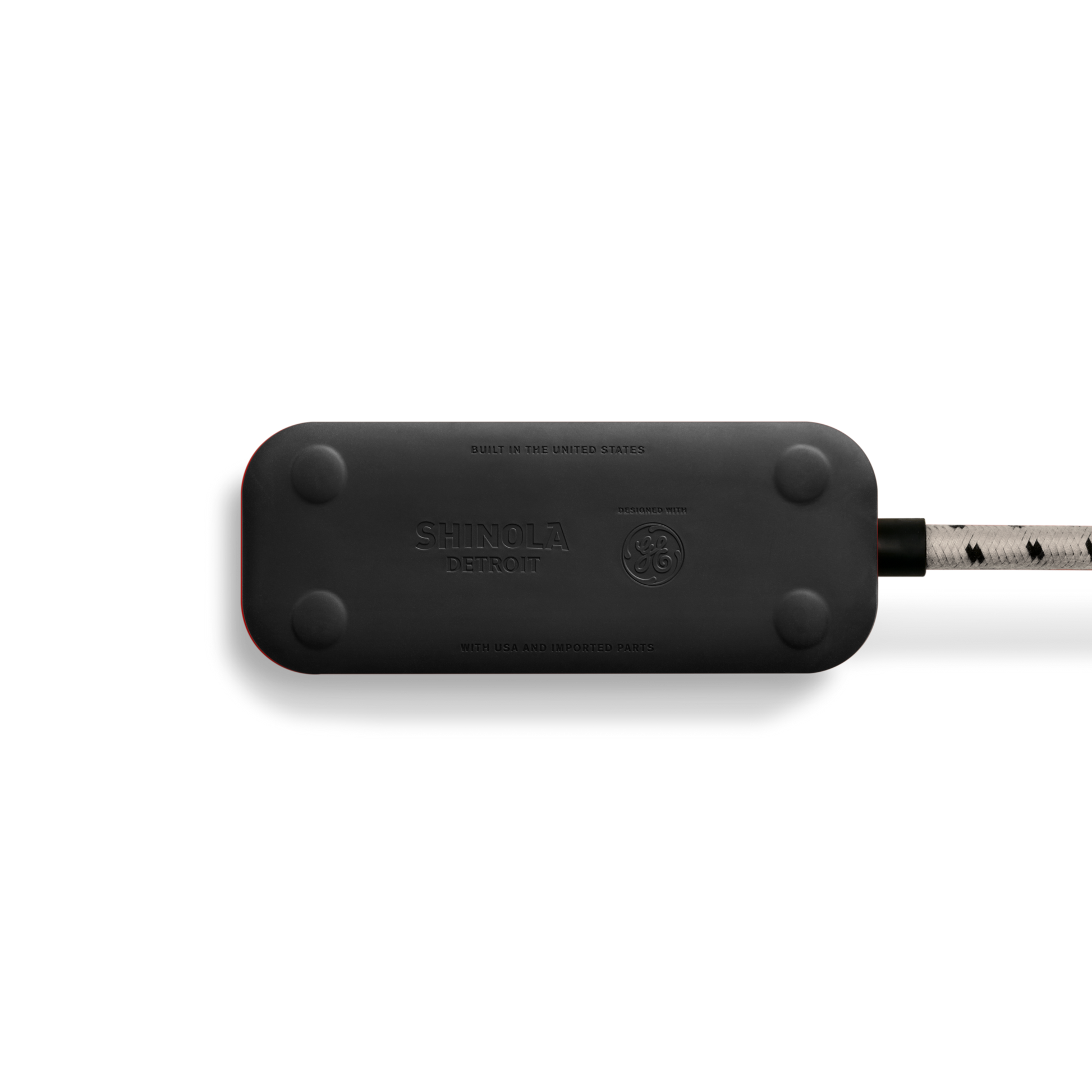 A Shinola 2 Port Power Supply - Stone, featuring die-cast metal accents, rounded edges, and a braided white and black cord, is photographed on a white background.