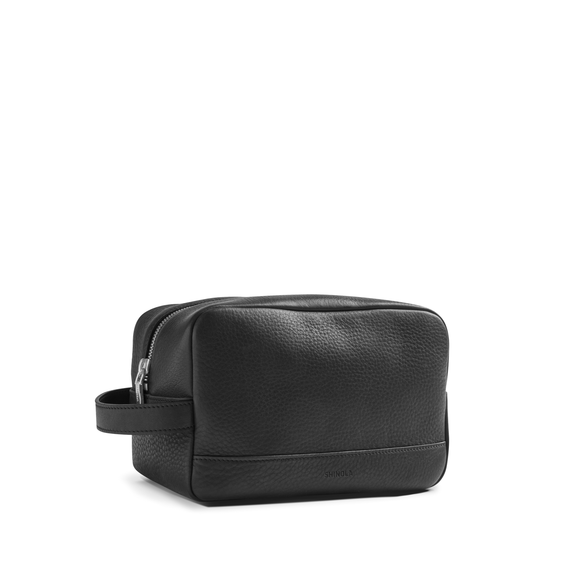 The Shinola Zip Travel Kit - Black features natural grain leather with a textured finish, a zippered top, side handle, and water-resistant lining. Shown against a plain white background.