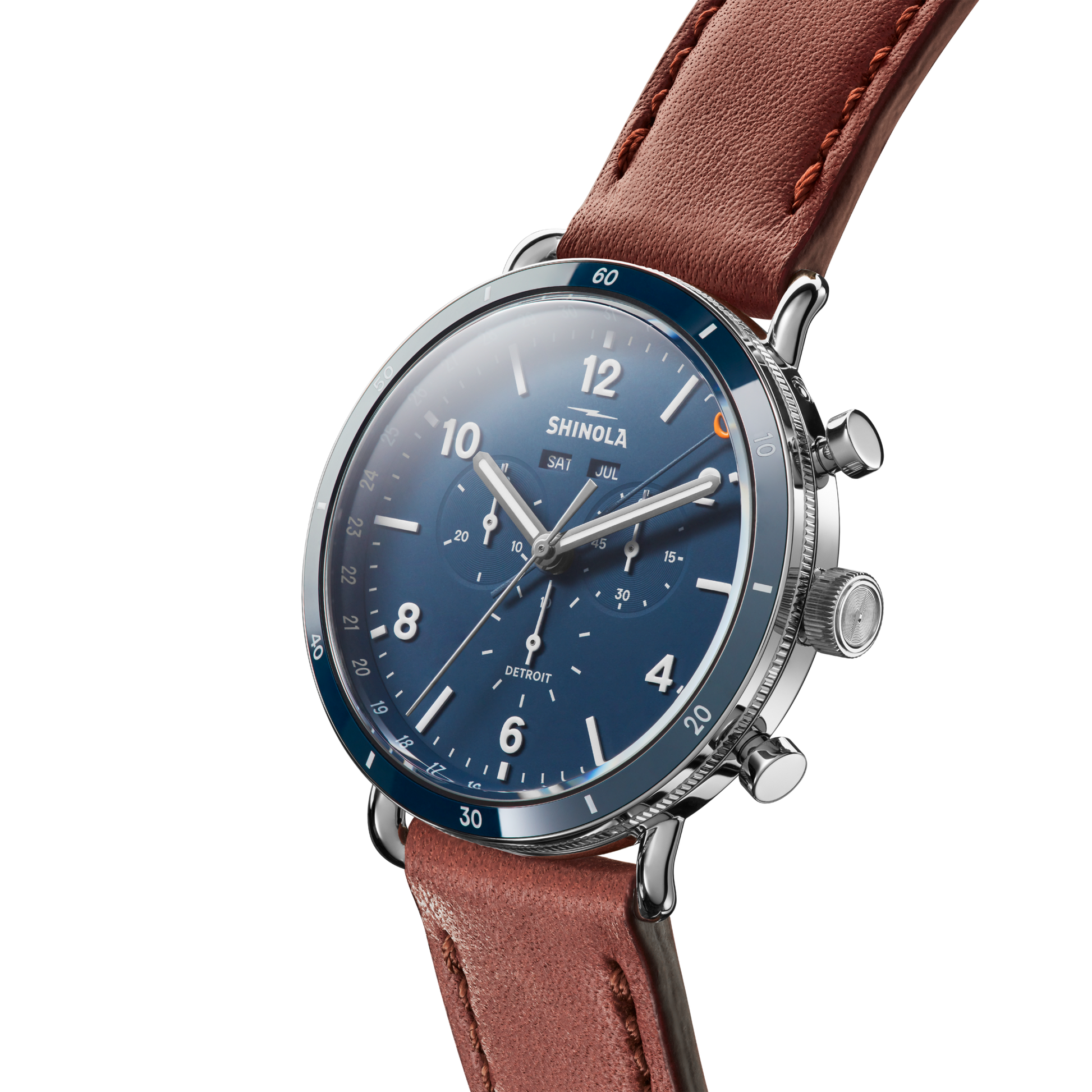 A close-up of the Shinola Canfield Sport Chronograph Watch - Midnight Blue shows its blue dial, silver case, brown leather strap, and chronograph subdials against a plain white background.