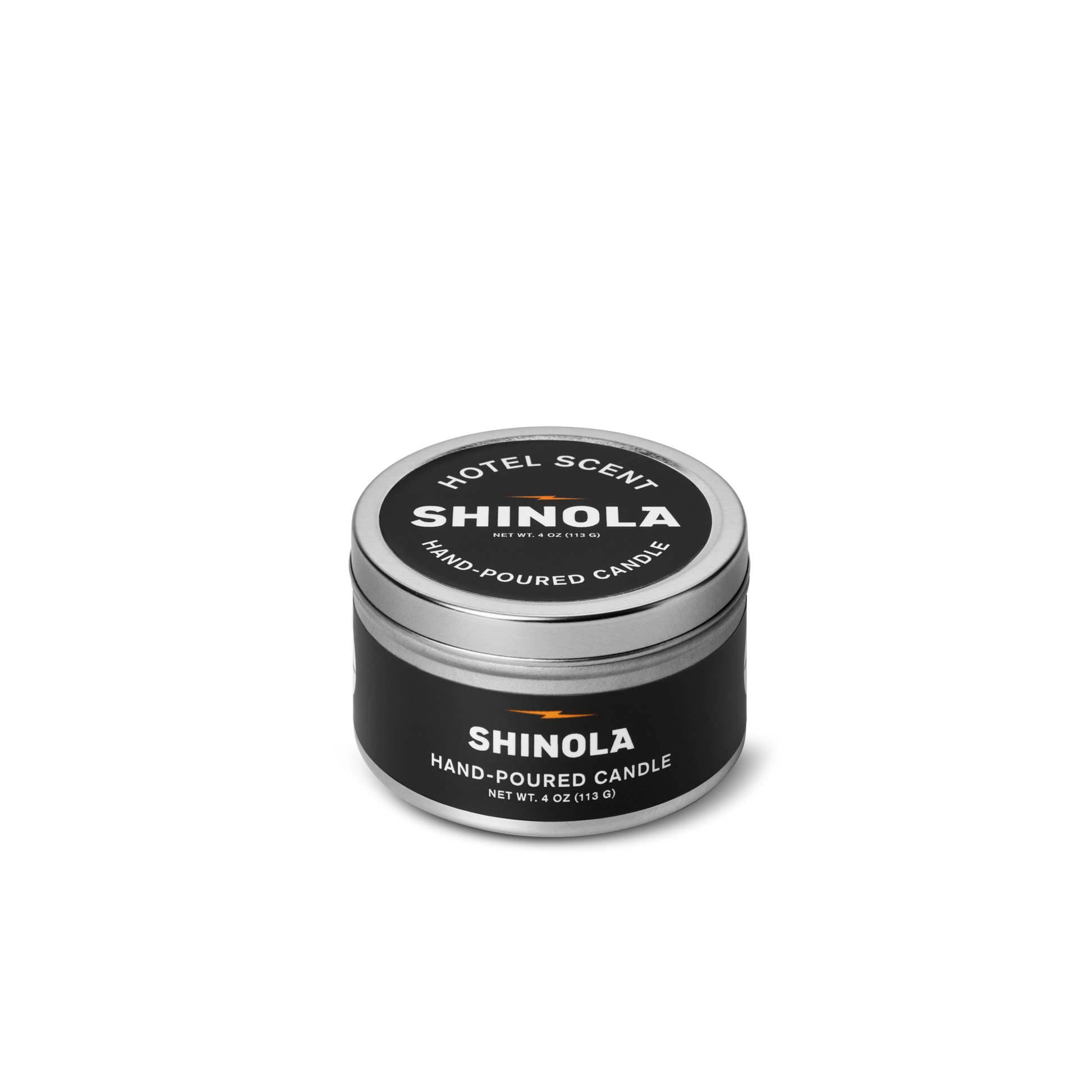 A small, round tin of the Shinola Hand Poured 4oz Travel Candle - Hotel, made from coconut soy wax. The black container has white text and a silver lid, shown against a plain white background.