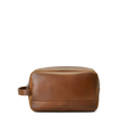 The Zip Travel Kit - Medium Brown by Shinola features navigator leather and a side handle, shown on a plain white background. Shinola’s brand name is subtly embossed near the lower front.