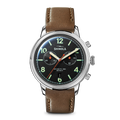 The Shinola Traveler Chronograph Watch - Black features a black dial, silver case, brown leather strap, neon green hour markers, two subdials, and orange, green, and white hands.