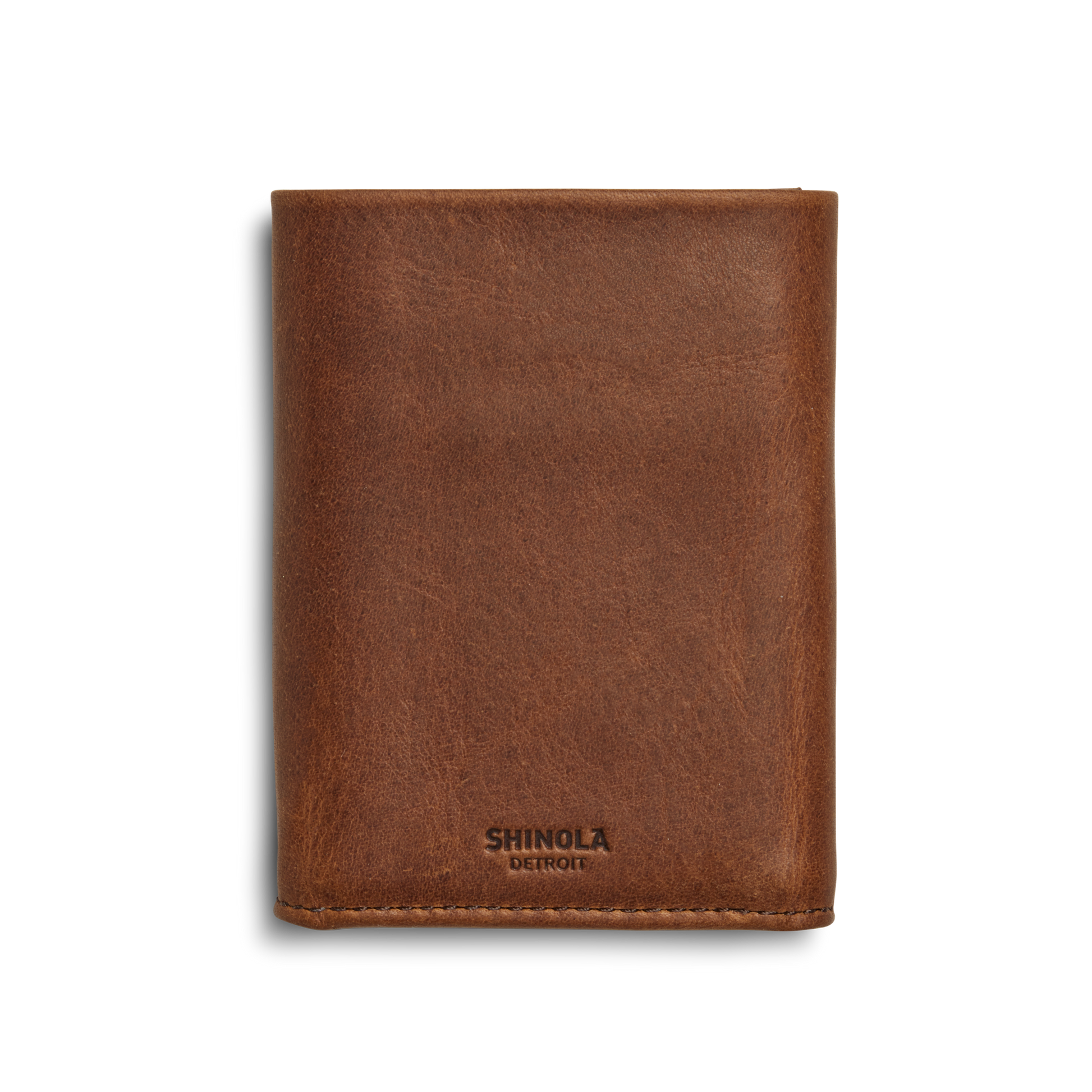 A Shinola Trifold Wallet - Medium Brown stands upright on a white background, featuring the brand embossed near the bottom edge and built-in RFID protection for added security.