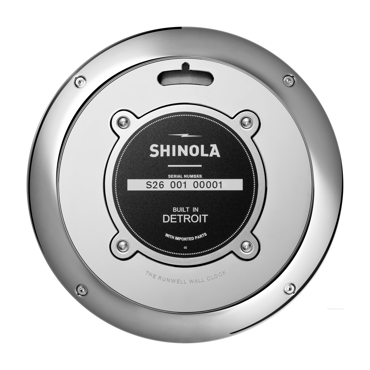A close-up of the back of a Shinola 14" Runwell Clock - Black shows its round chrome casing and a black label displaying the serial number and stating "Built in Detroit with imported parts.