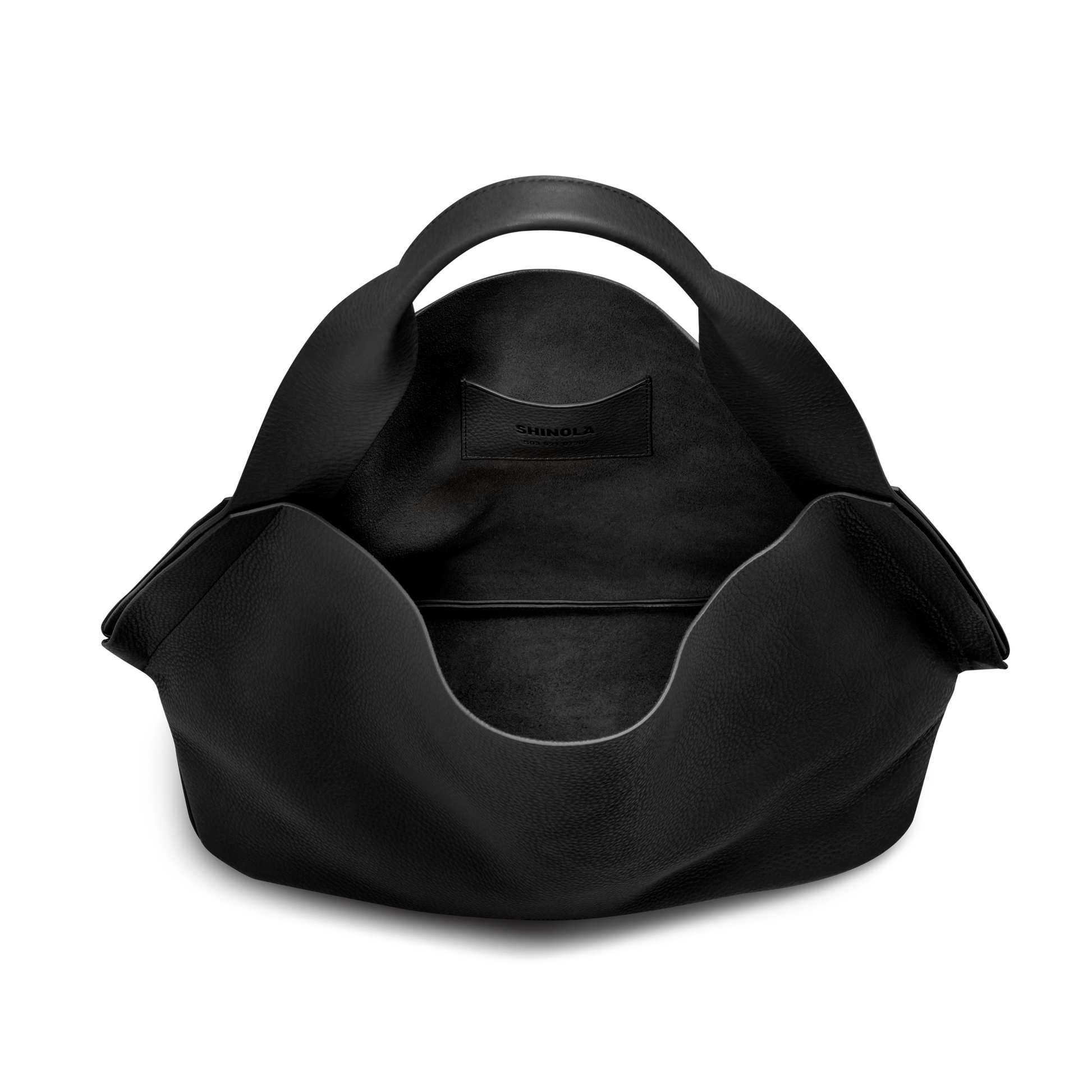 The Derby Shoulder Bag - Black by Shinola is a spacious leather bag with a rounded handle, an exterior leather card pocket displaying the brand name, and a large open compartment for easy organization.
