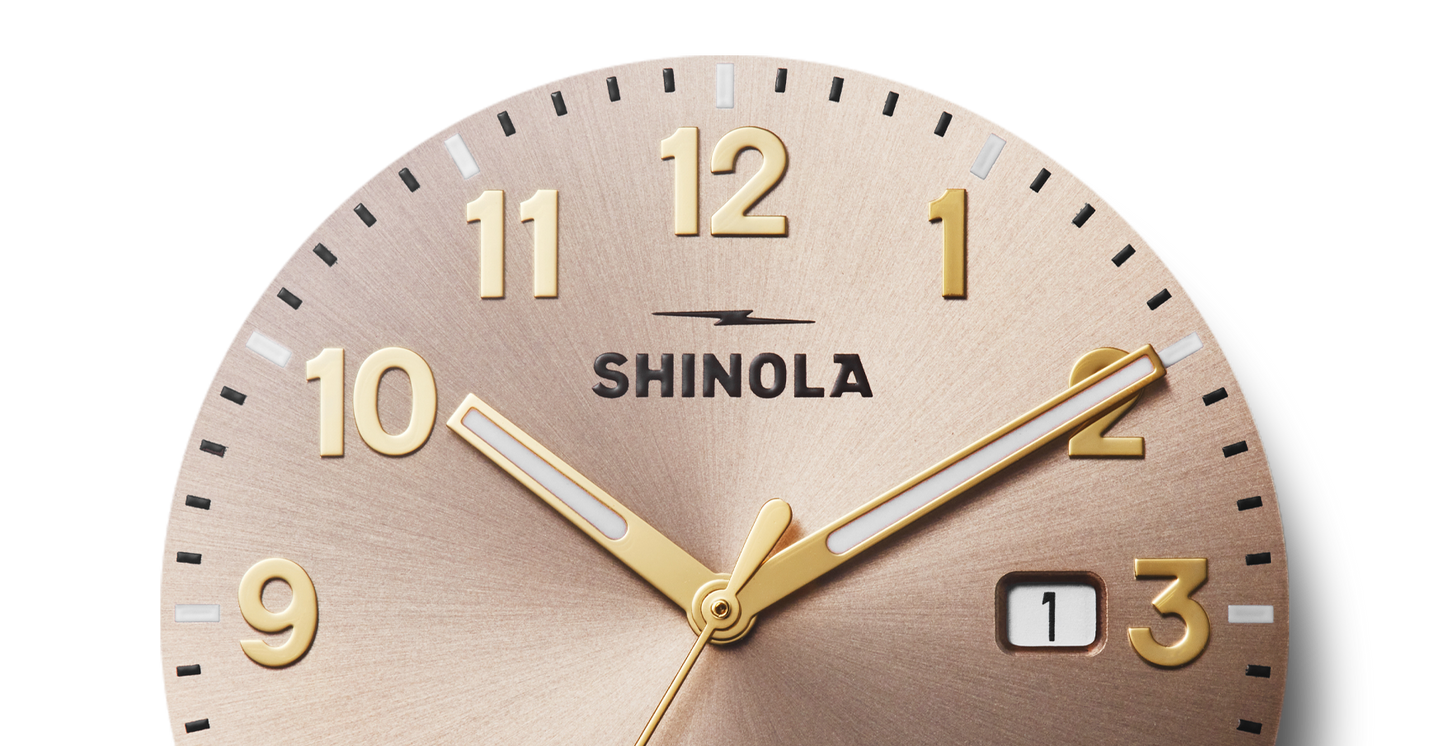Close-up of a Shinola Detrola Watch - Nude, showing the time as 10:10. Features bold gold numbers, matching hands, and a date window at 1—showcasing classic American design and durable craftsmanship.