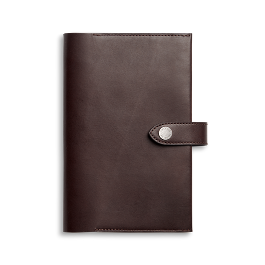 The Shinola Medium Snap Journal Cover in dark brown Vachetta leather features a flap closure with a round silver snap, shown against a plain white background.