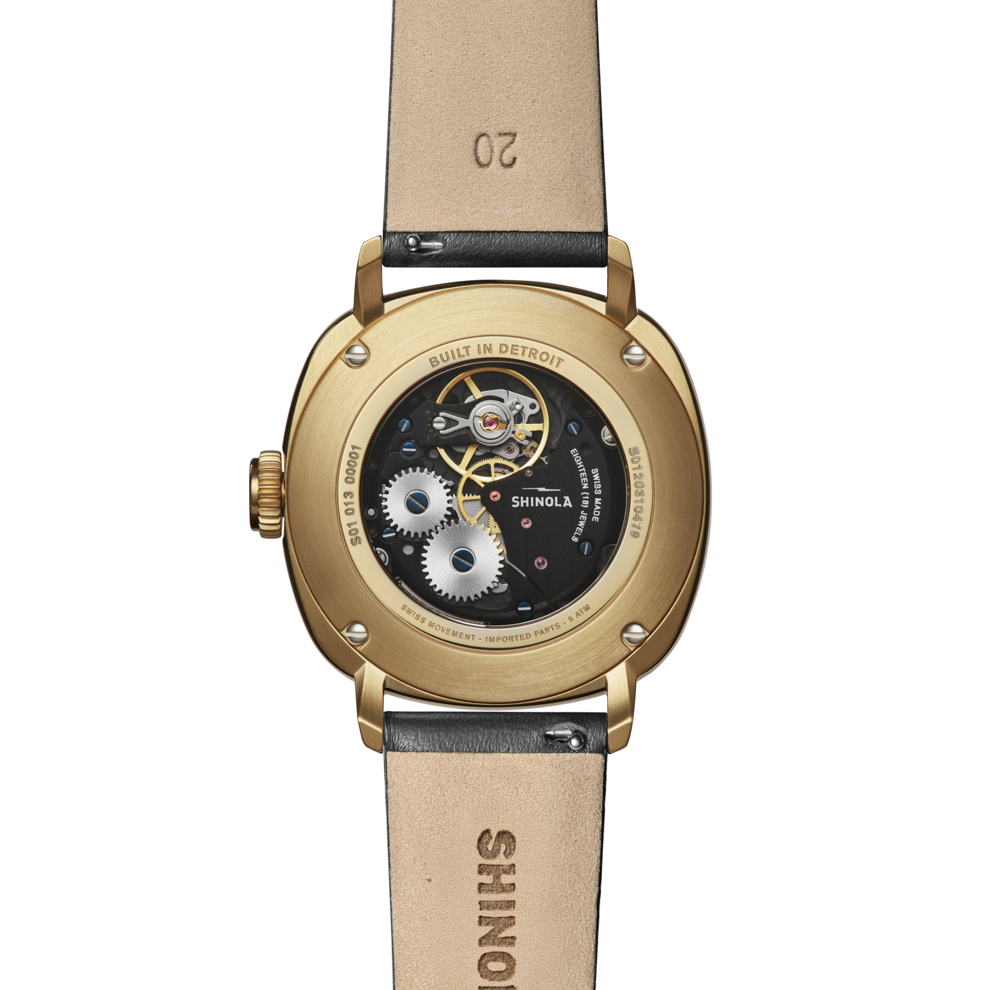 Back view of the Shinola Mechanic Watch - Dominos shows its gold case, exhibition case back with visible gears, brown leather strap, and "BUILT IN DETROIT" engraved around the edge.