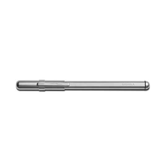A matte silver Stainless Steel Studio Pen by Shinola with a clipped cap rests horizontally on a white background. The SHINOLA brand name is engraved near the end of this elegant pen's stainless steel barrel.