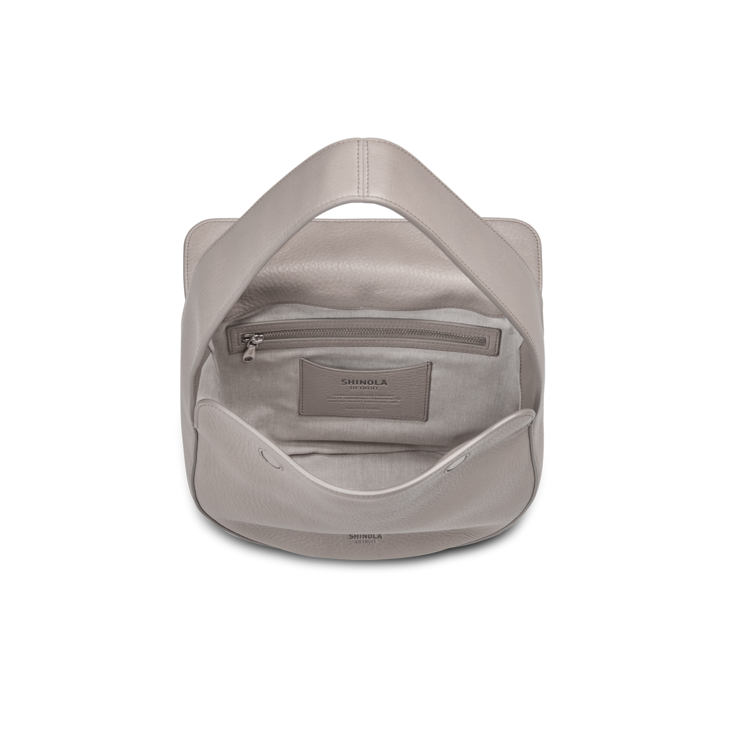 A top-down view of an open Shinola Small Shoulder Bag - Taupe in natural grain leather, revealing the interior with a zippered pocket and slip pocket, both displaying SHINOLA branding.