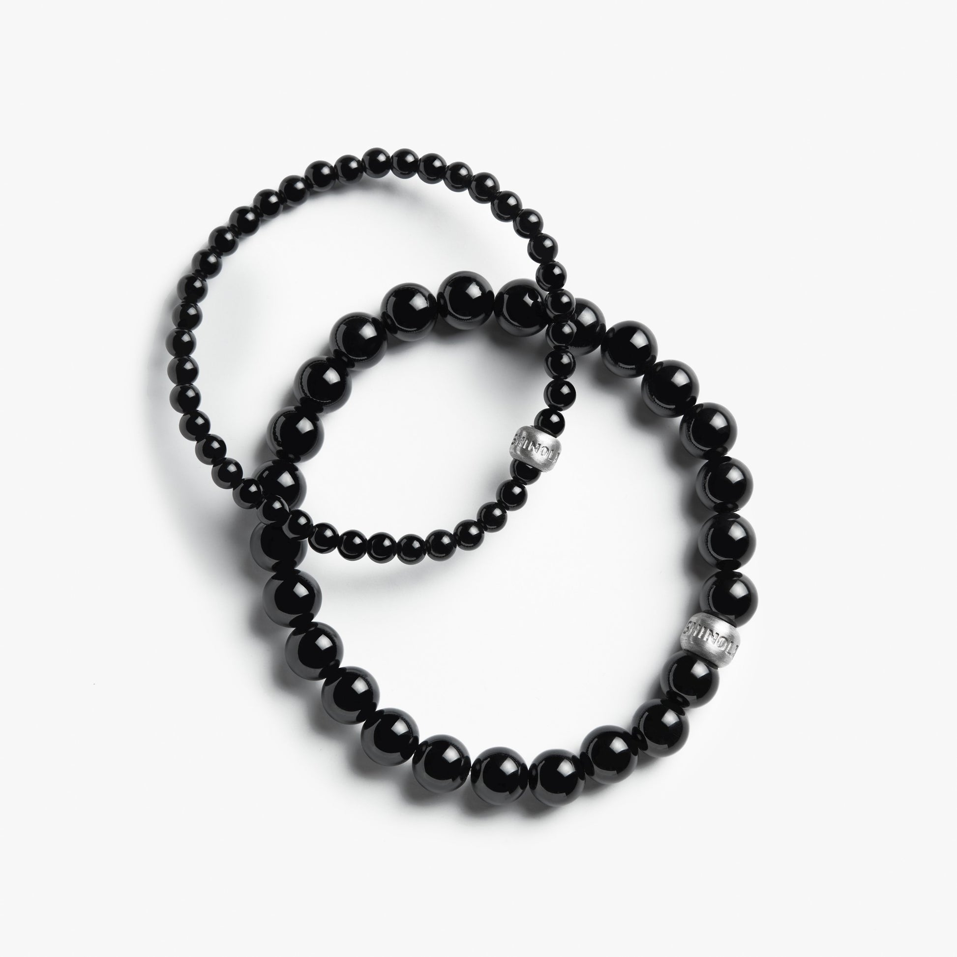 Two Shinola 4mm Beaded Onyx Bracelets, featuring sterling silver accent beads and glossy black onyx stones—one with larger and one with smaller beads—are displayed overlapping on a white background.