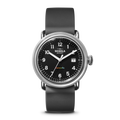 The Shinola Detrola Watch in black features a round face with white numerals, orange second hand, date window, and black leather strap. "Detroit" appears in colorful letters above 6 o'clock.