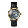 The Shinola Runwell Watch - MOP Dominos features a gold stainless steel case, black leather strap, black and blue marbled face, gold hour markers, and gold hands, shown against a plain white background.