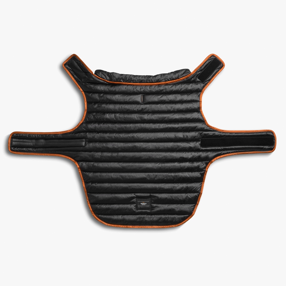 The Shinola Reversible Puffer Dog Coat in orange and black features padding, quilting, wide Velcro straps, and a torso-wrapping design. Displayed flat on a white background.