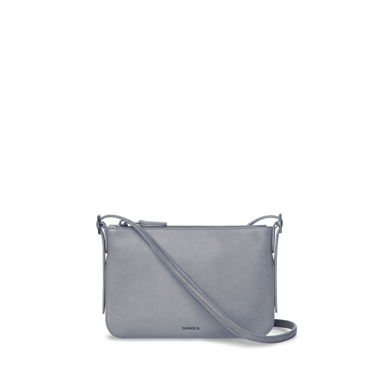 The Small Bixby Crossbody - Mist by Shinola is a sleek, light gray Natural Leather bag with a rectangular shape, adjustable strap, top zipper closure, and subtle branding—perfect for everyday use.