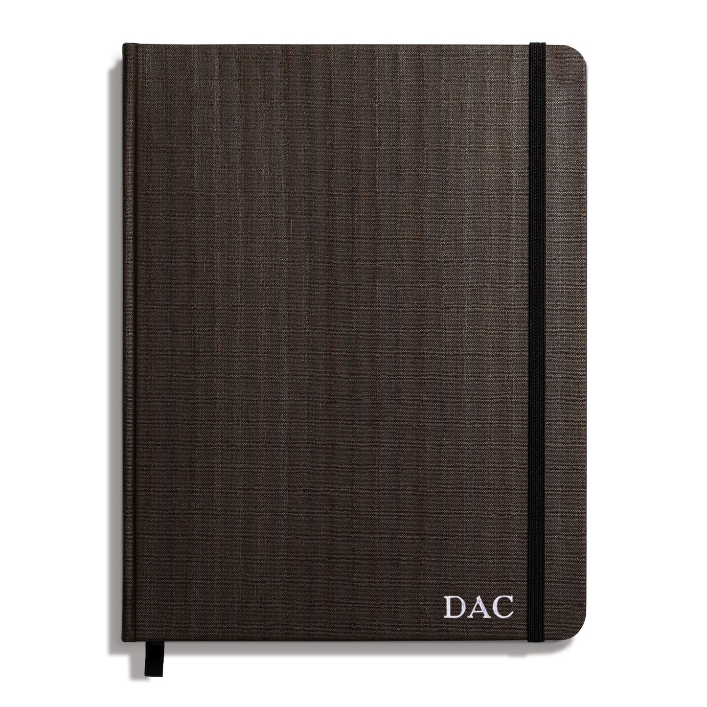 The Shinola Large Hard Ruled Journal in Espresso features a dark brown linen cover, hard Smyth-sewn binding, black elastic band, ribbon bookmark, and white "DAC" initials printed on the bottom right corner.