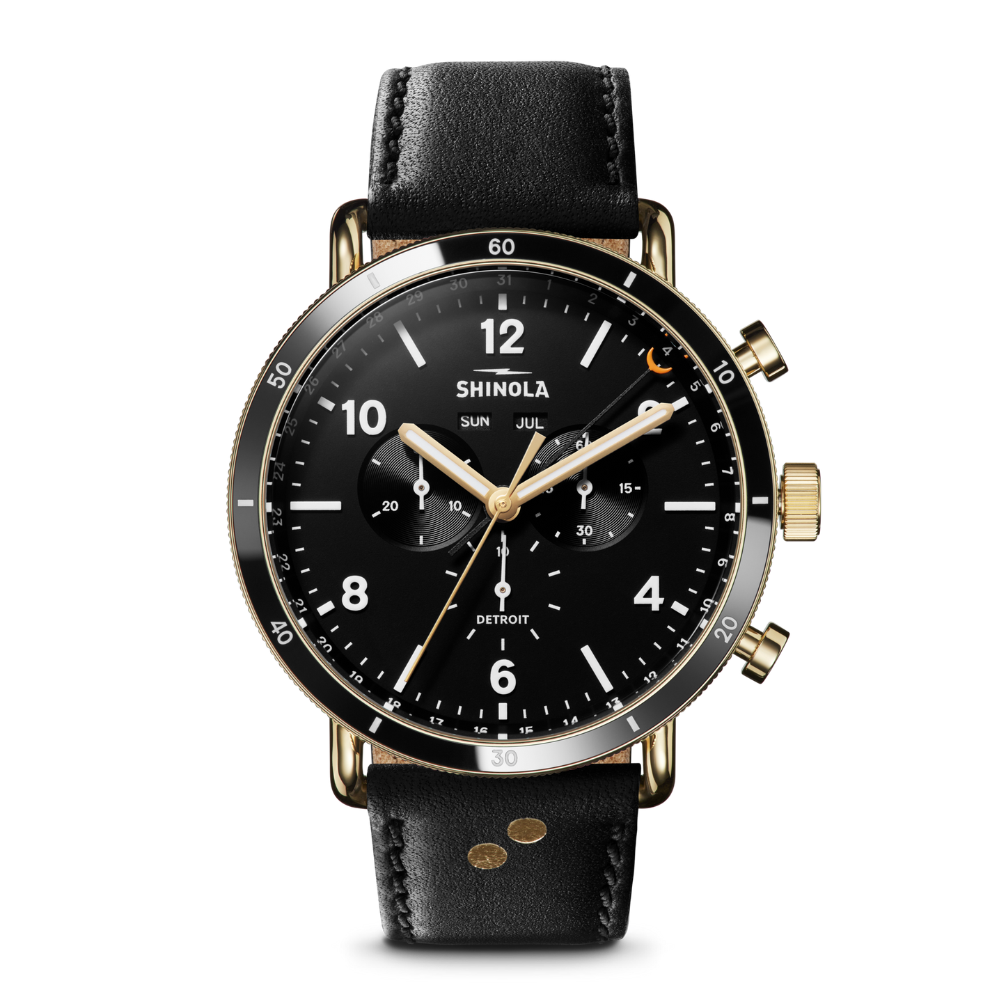 The Shinola Canfield Sport Watch - Dominos features a black and gold chronograph face with three sub-dials, a date window, white hour markers, two gold pushers, and is finished with a black leather strap. It also displays the day and month.