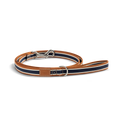 The Shinola Nylon Dog Leash - Brand Stripe features navy, white, and brown stripes, a silver clasp, D-ring, and stitched leather patch near the handle. Durable and stylish, it's shown coiled on a white background.