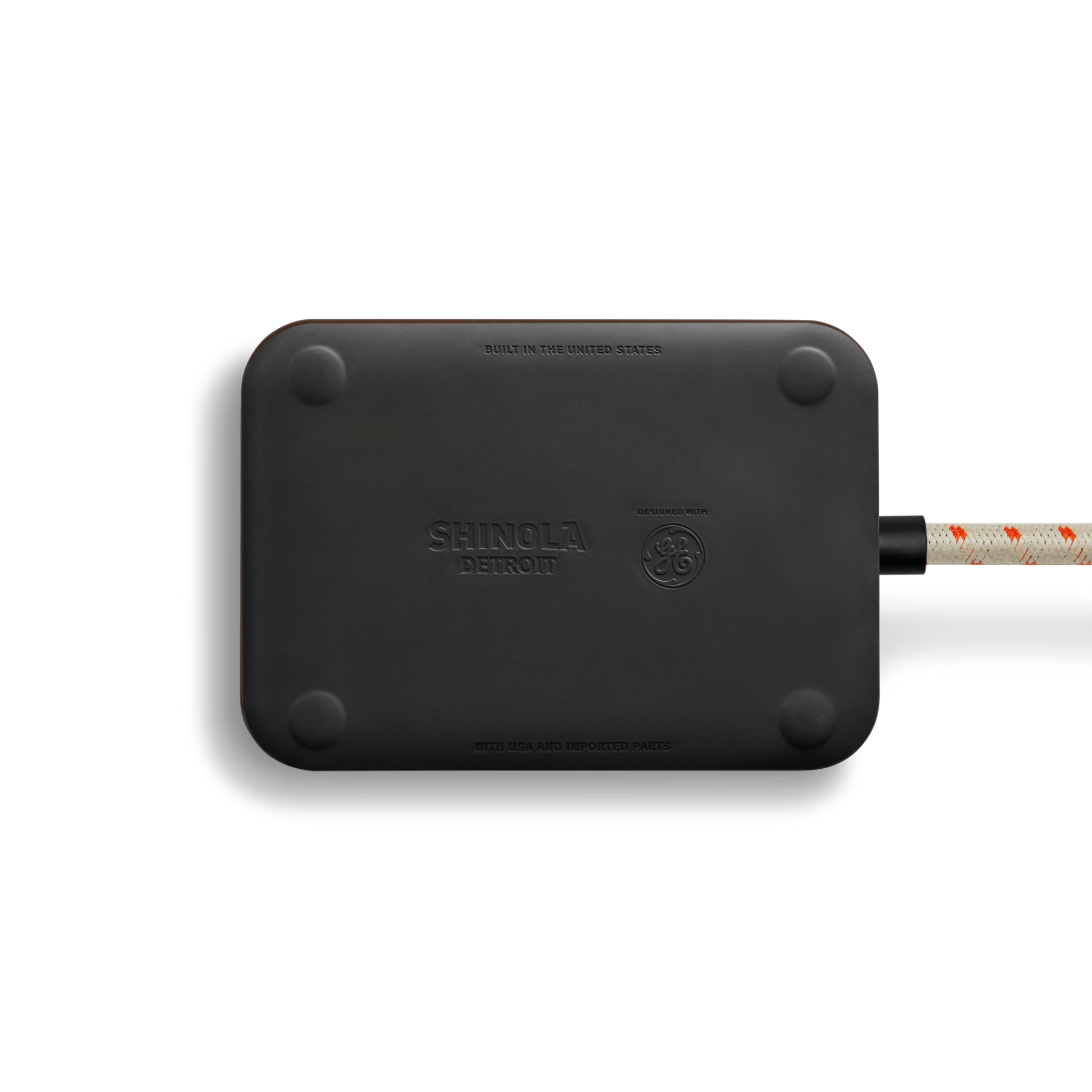 The Shinola 5 Port Power Supply - Black is a sleek rectangular charger with rounded corners, branded with embossed Shinola logos, and features a custom braided extension cord. It offers versatile USB-A and USB-C charging for your devices.