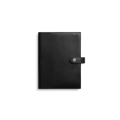 The Shinola Large Journal Cover in black features closed Italian Vachetta leather with a snap button strap closure, displayed against a plain white background.