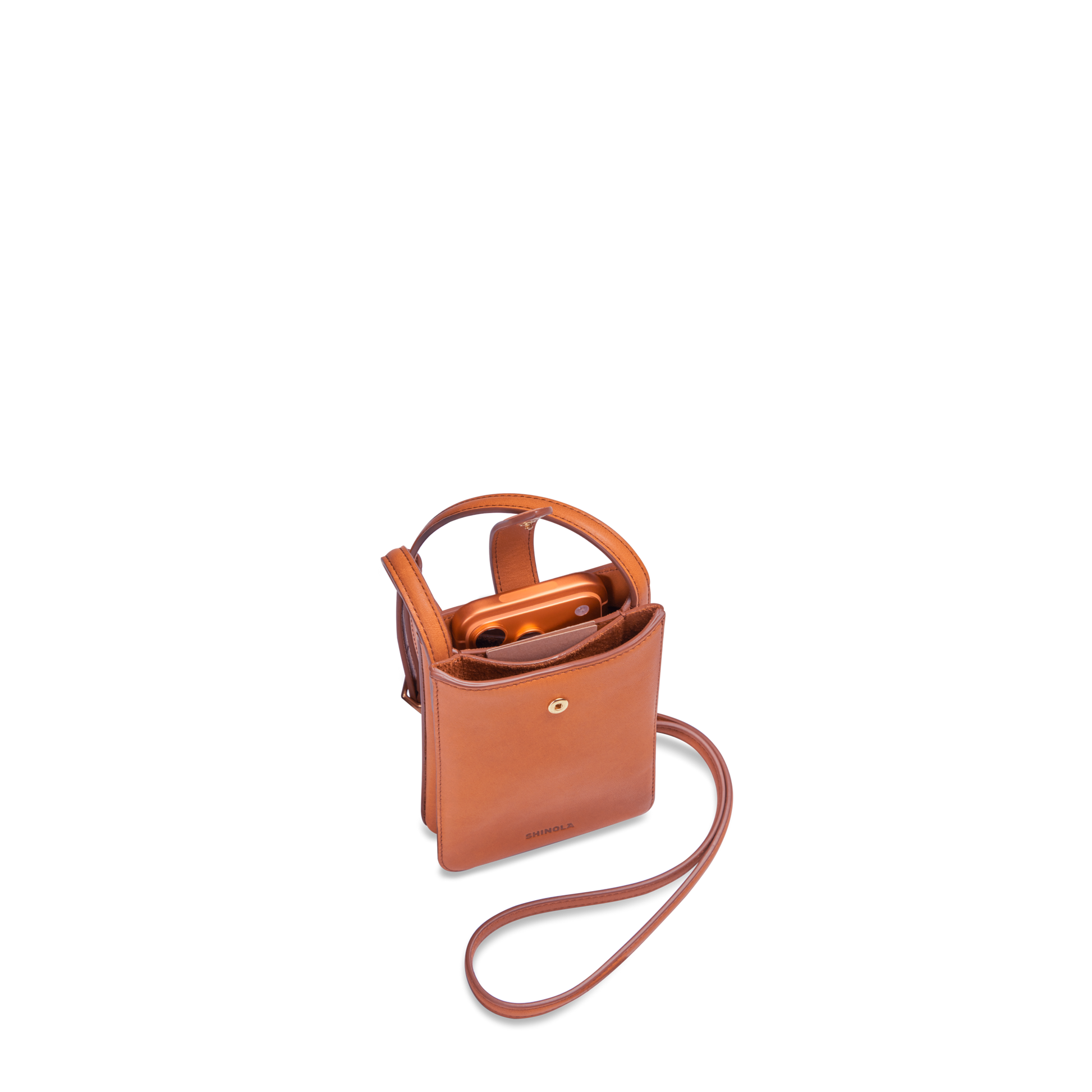 The Shinola Bixby Phone Crossbody - Rust is a compact, natural leather bag with a snap closure, shown open on a white background with a smartphone partly visible inside.