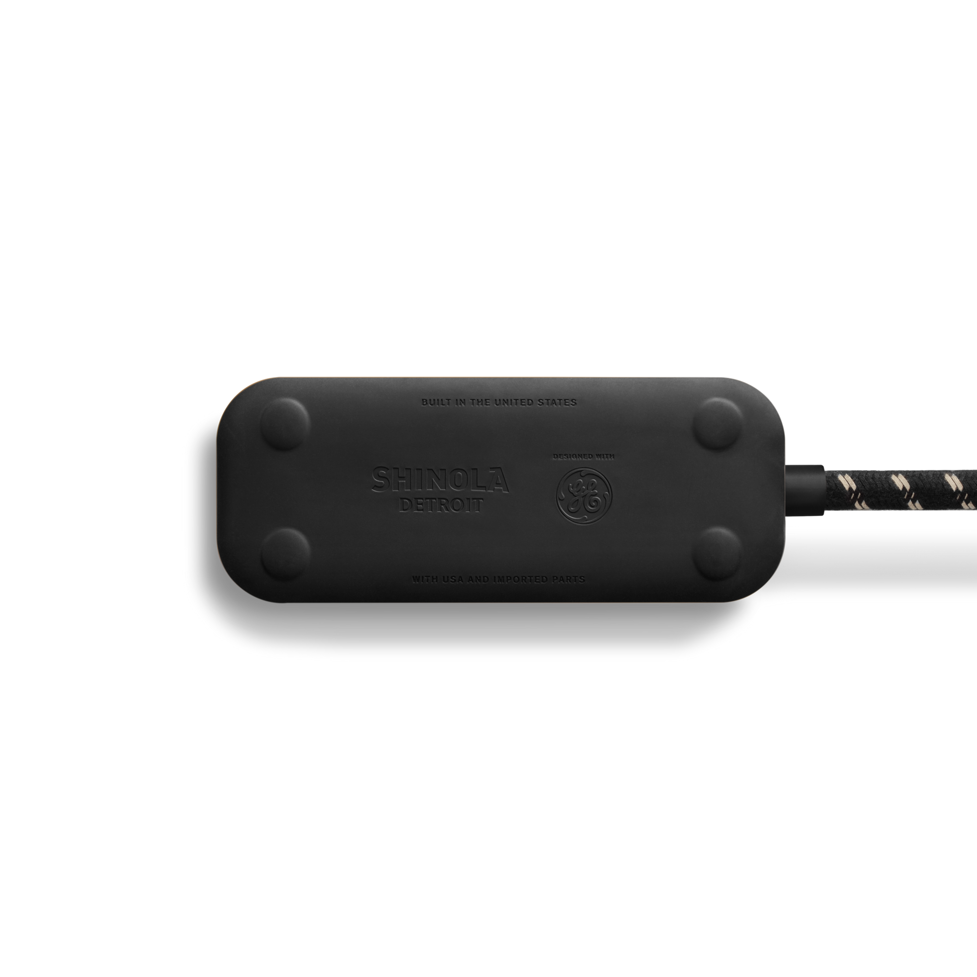 A Shinola 2 Port Power Supply in Tangerine with a durable braided cord, rounded edges, and USB-A/USB-C quick-charging ports is shown on a white background. "Shinola" is embossed on the surface.