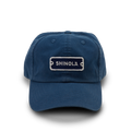 The Shinola Cotton Twill 6 Panel Cap is crafted from garment-dyed cotton twill in blue, featuring a white-stitched SHINOLA patch, visible stitching, curved brim, and a leather strap closure.