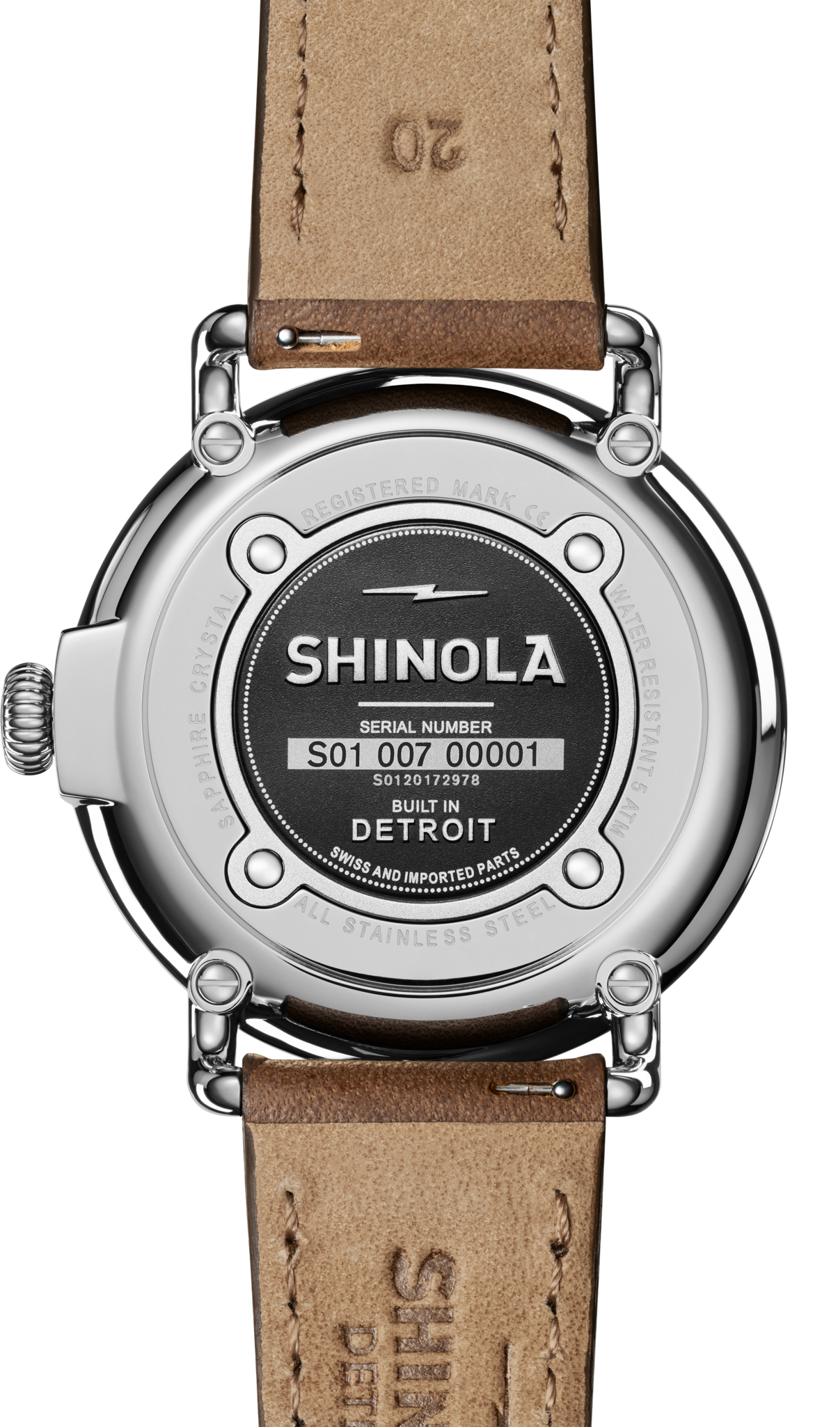 The back of a Shinola Runwell Date Watch - Blue features a silver case engraved with Shinola, Serial Number S01 007 00001, and Built in Detroit. A brown leather strap and a glimpse of its stylish blue dial complete the look.
