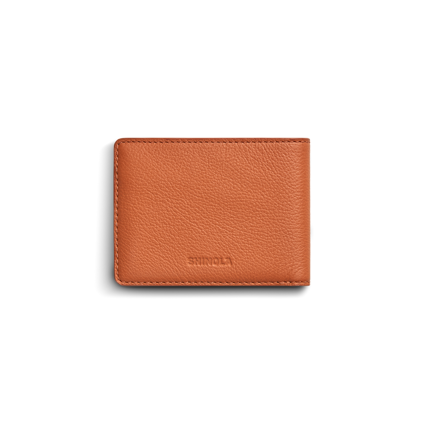 A closed Shinola Canfield ID Bifold wallet in rust-colored pebbled leather with a textured surface, stitched edges, and subtle brand embossing is shown against a white background.